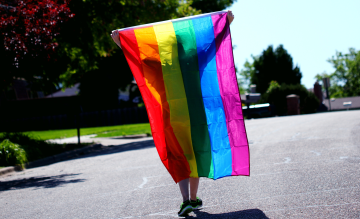 Person geht mit Regenbogenflagge